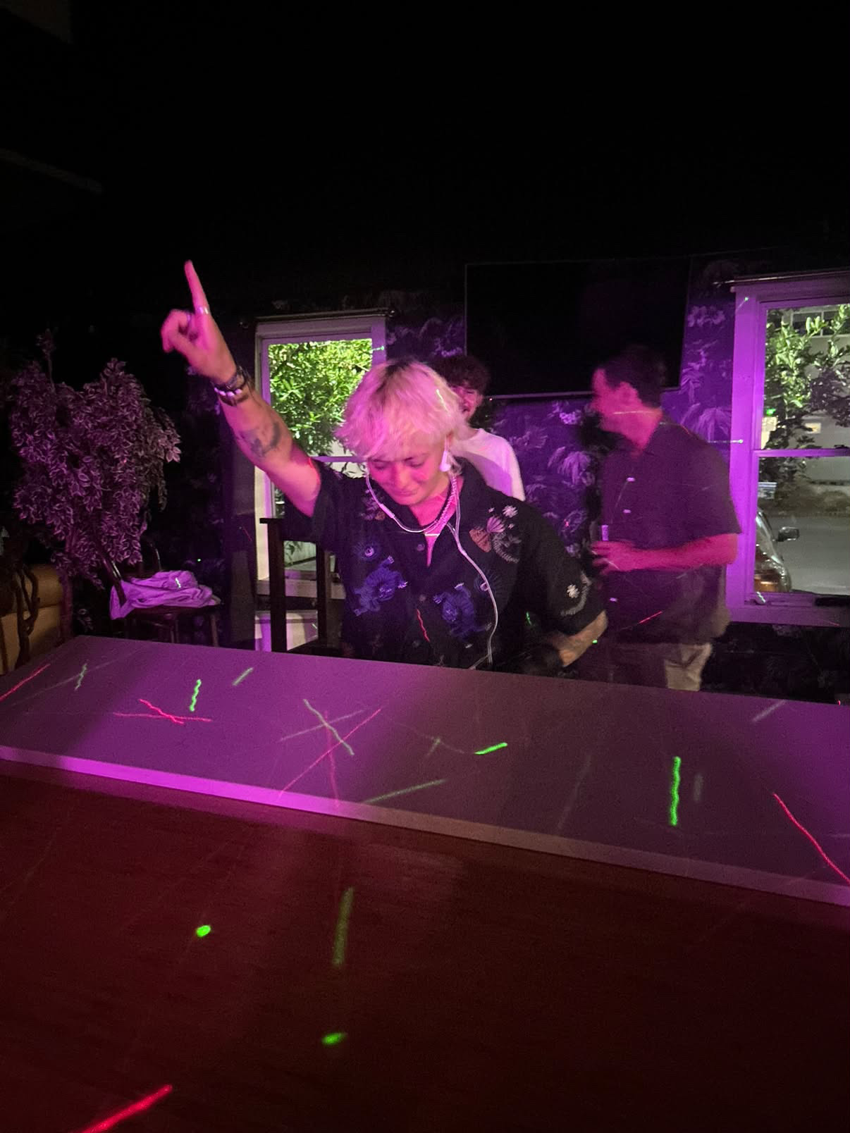 Brooke Wylie pointing up mid-set under purple lights